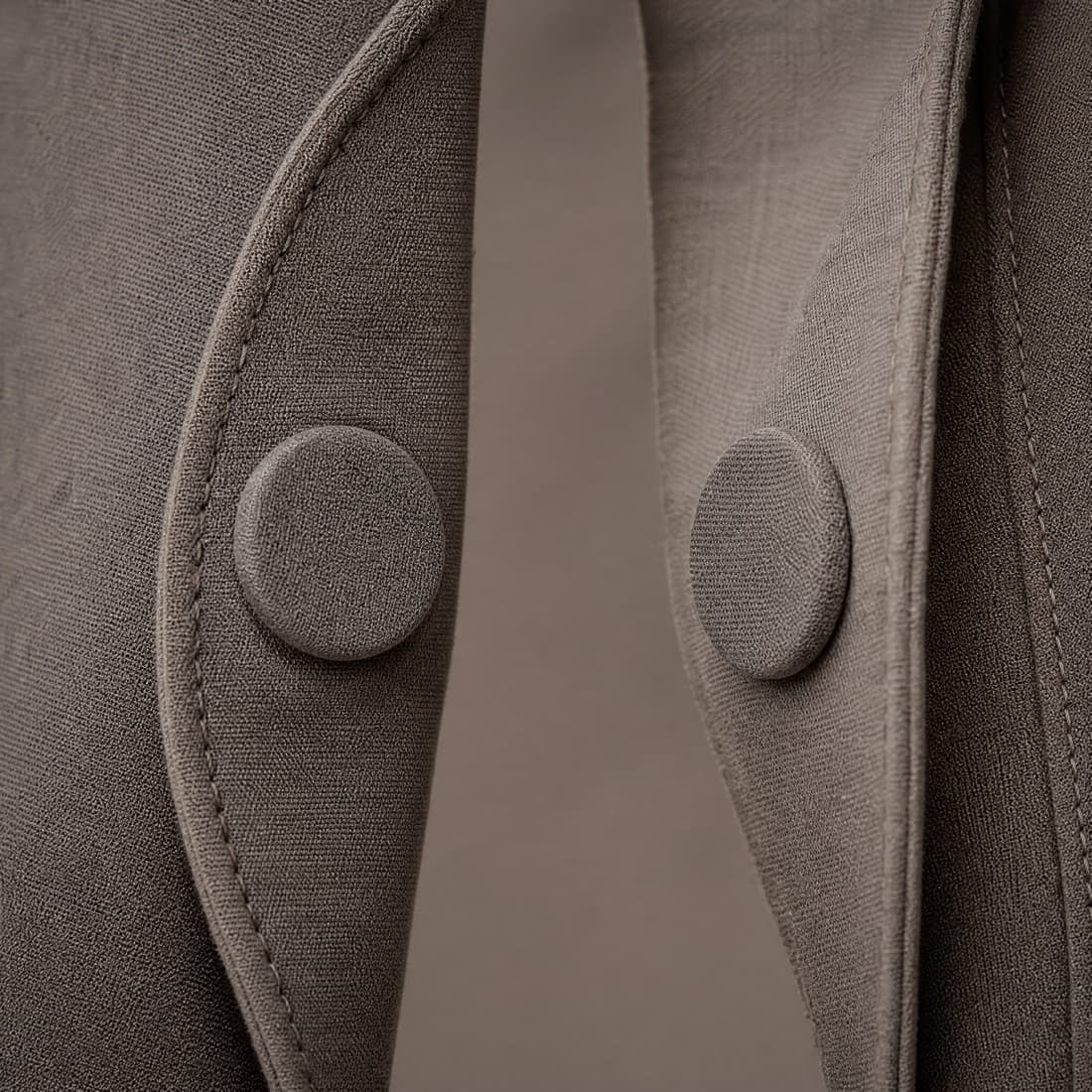 Close-up of the same magnetic closure separated, the placket peeled open so the two fabric-covered discs sit apart on their facing panels.