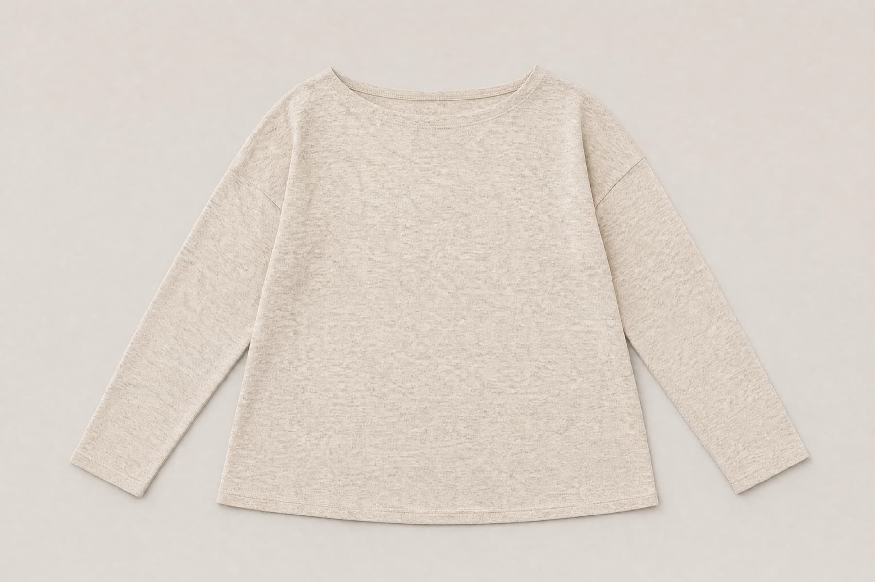 An oatmeal jersey top with a wide boat neckline, fully closed and laid flat. The side seams read as ordinary seams and no fastener is visible anywhere on the garment.