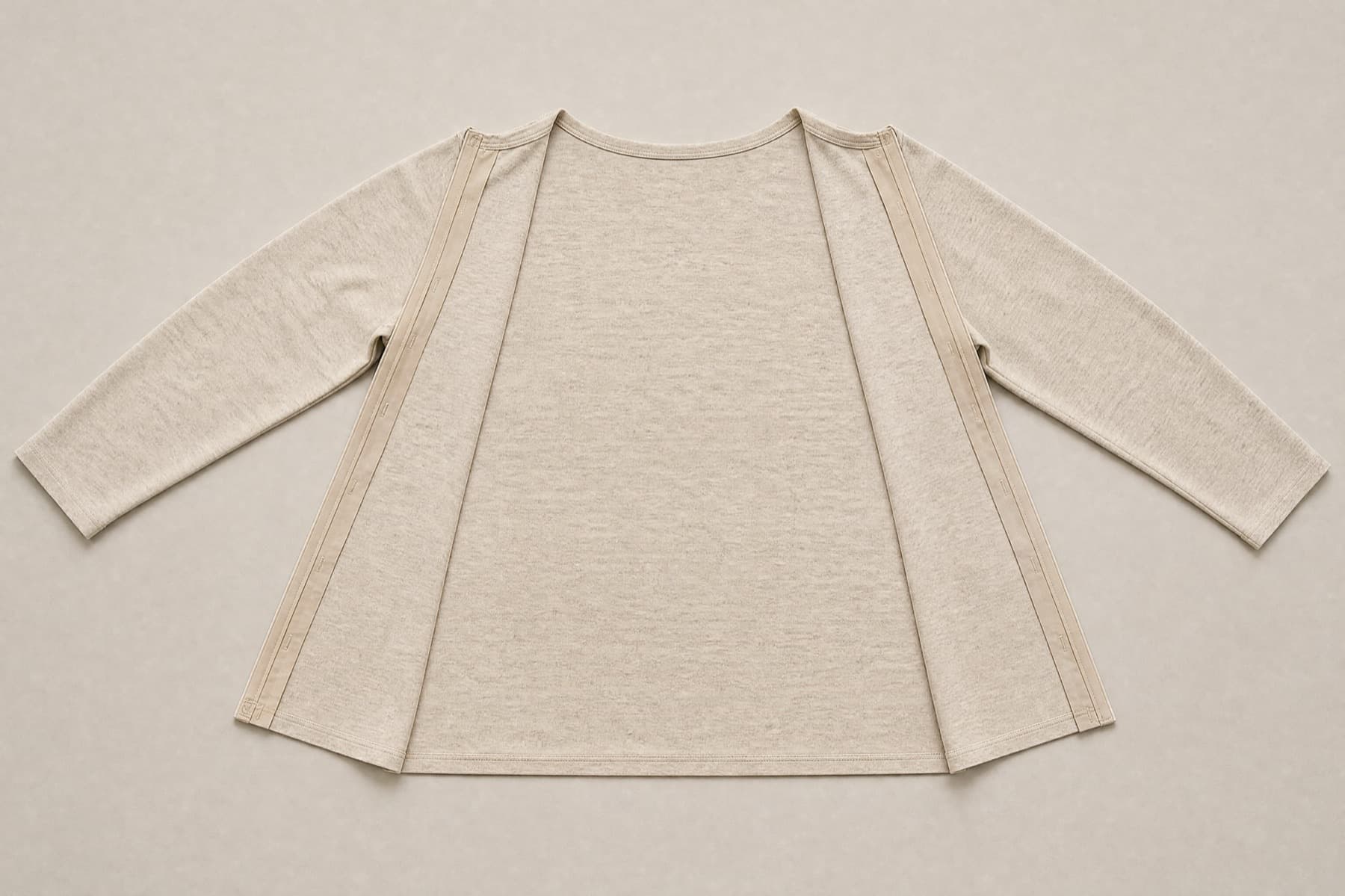 The same top opened along both side seams and spread out completely flat, front panel and back panel lying side by side with the closure strips visible down each open edge.