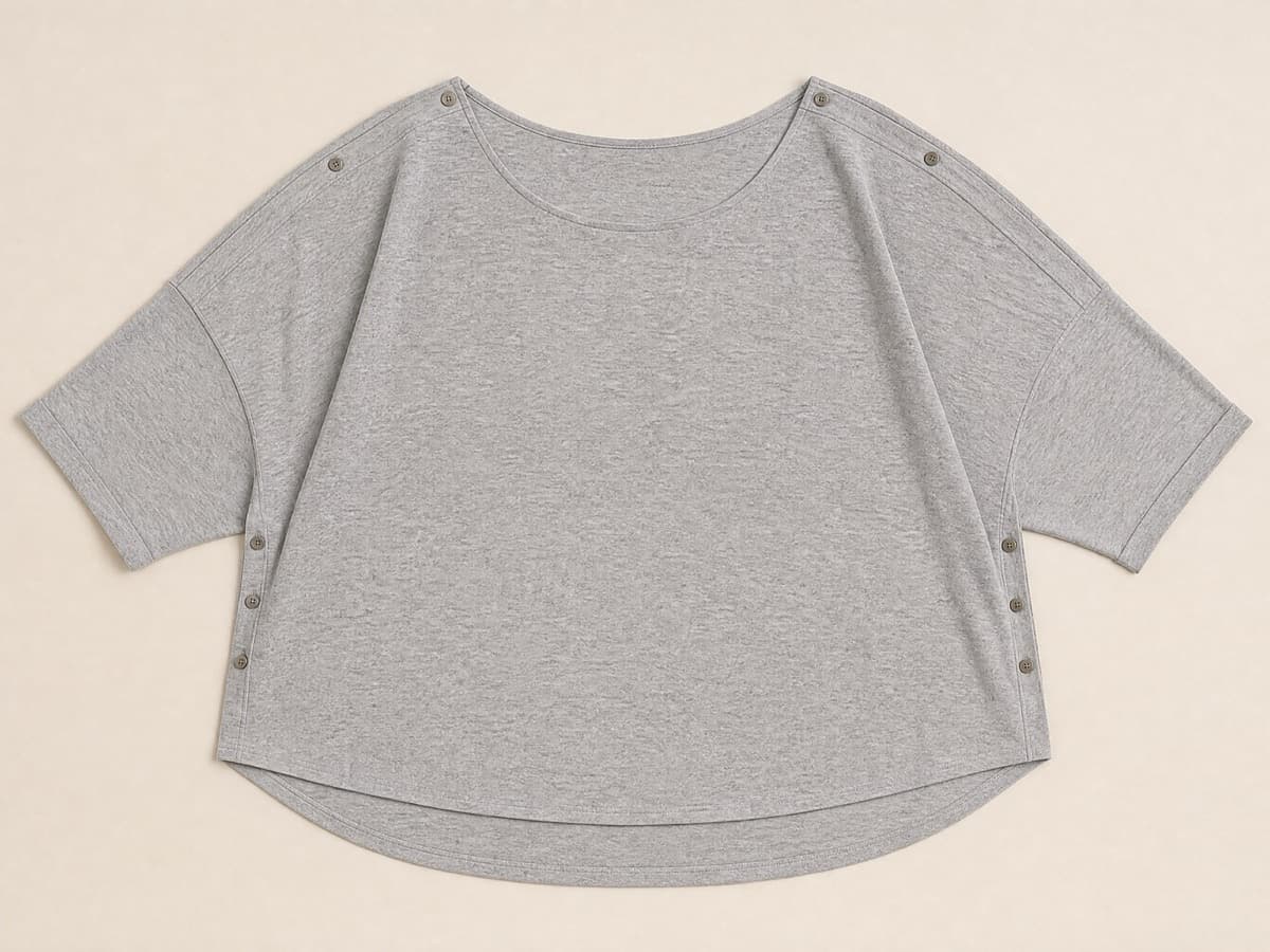 A generously cut warm grey jersey top laid flat, wide through the body and wide at the neckline, relaxed and unstructured.